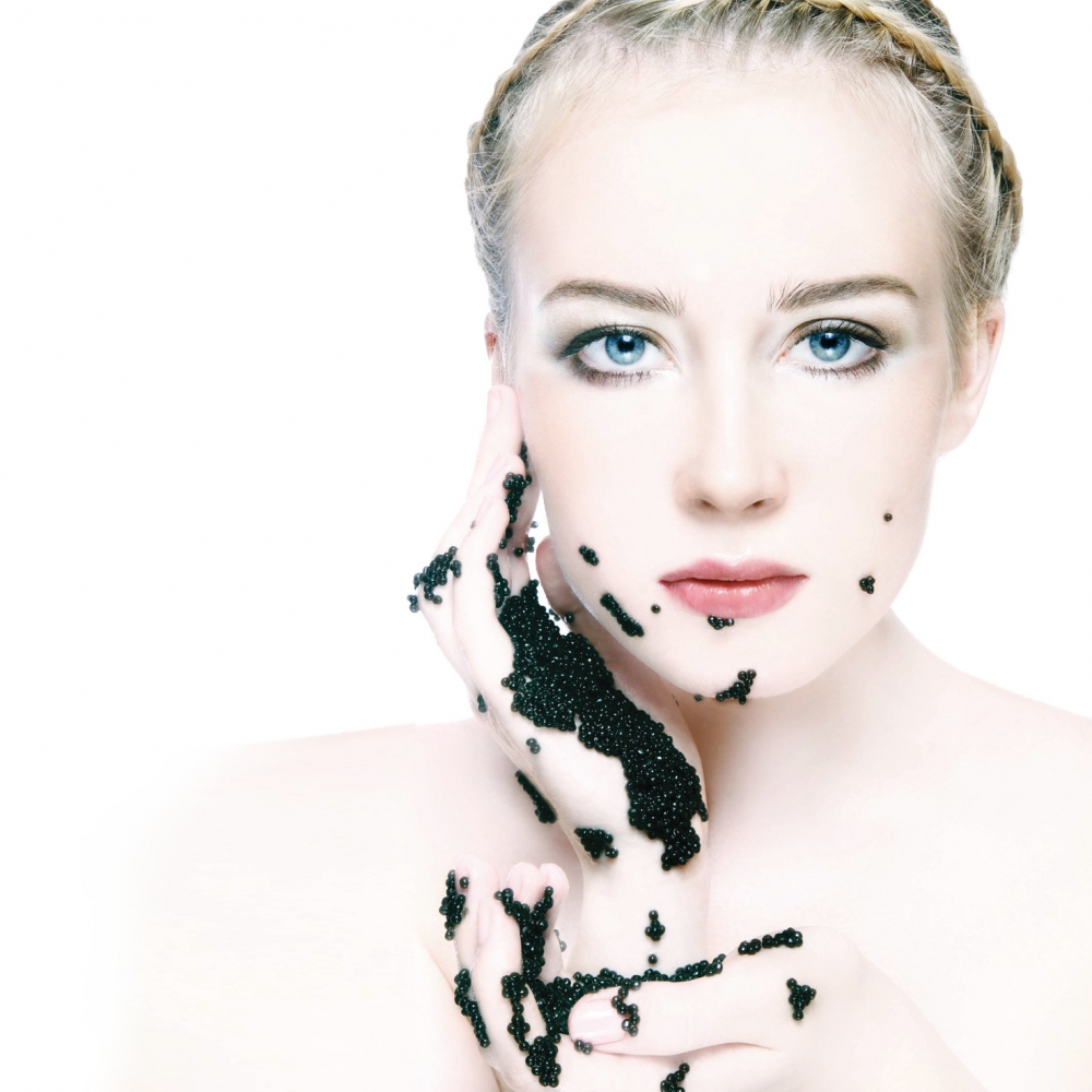 Portrait of young beautiful blond woman with black caviar in hands